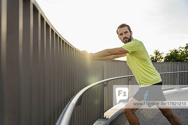 Bearded man stretching standing on footbridge