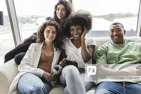 Smiling young woman playing video games with friends