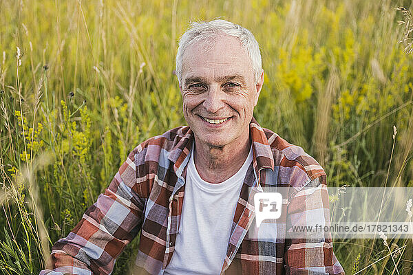 Happy farmer with white hair sitting in front of plants