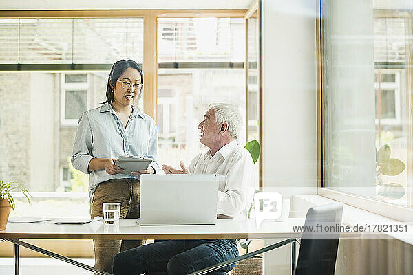 Happy senior businessman discussing work with colleague in office