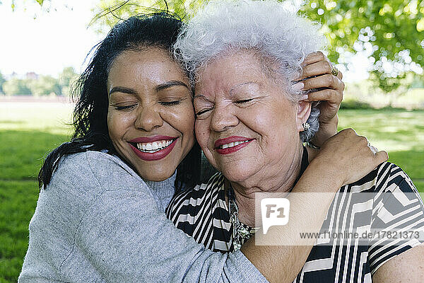 Happy woman embracing senior mother in park