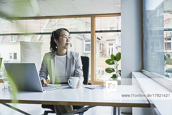 Thoughtful businesswoman with coffee cup at work place