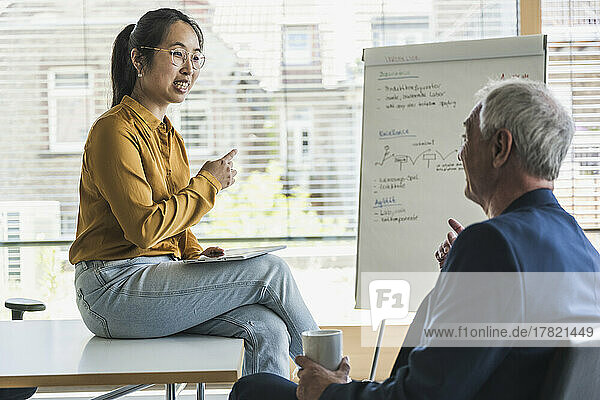 Smiling businesswoman with colleague discussing work in office