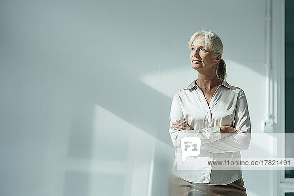 Senior businesswoman standing with arms crossed in office