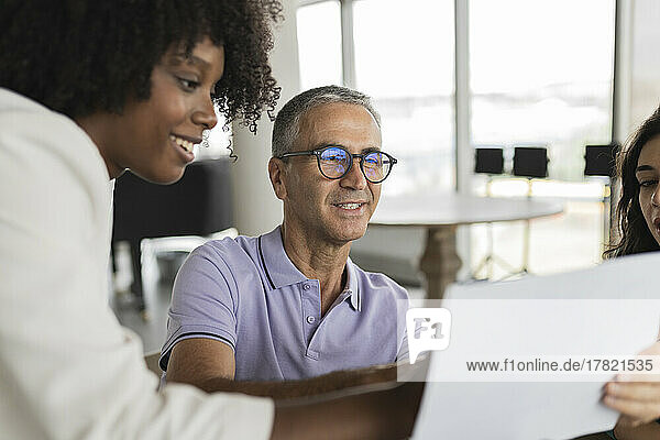 Smiling mature businessman discussing document with businesswomen