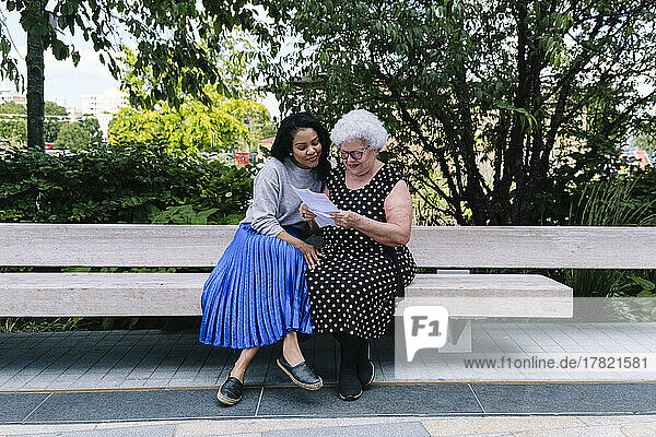 Mutter liest Brief  Tochter sitzt auf Bank im Park