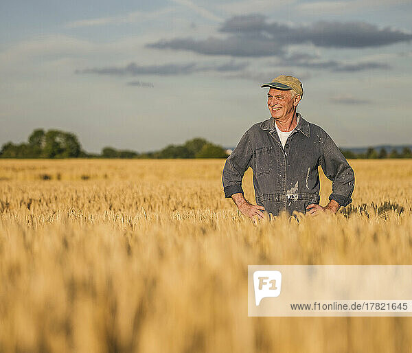 Happy senior farmer standing in wheat farm