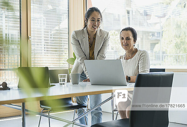 Happy businesswoman discussing work with colleague at work place