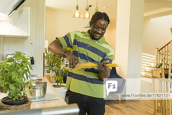 Young man removing uncooked spaghetti from jar in kitchen