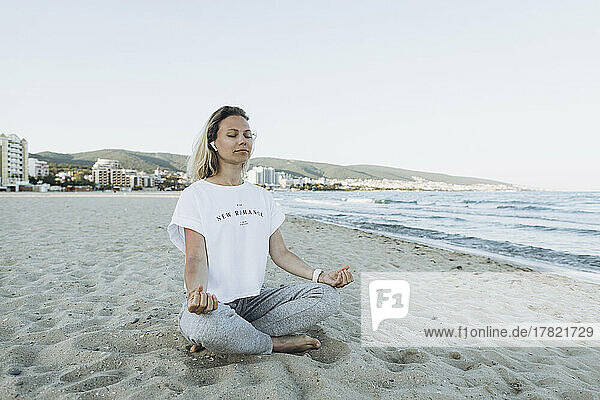 Smiling woman with eyes closed meditating at beach
