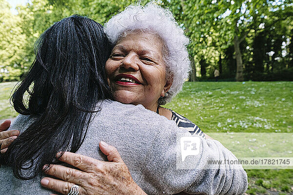 Smiling mother embracing daughter in park