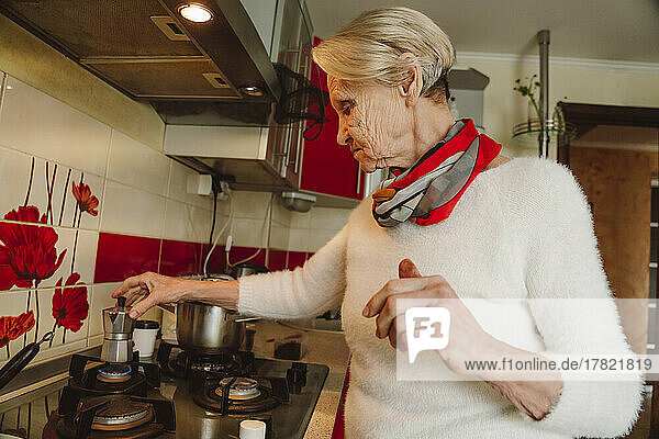 Ältere Frau bereitet zu Hause in der Küche Kaffee zu