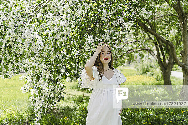 Happy pregnant woman standing in park