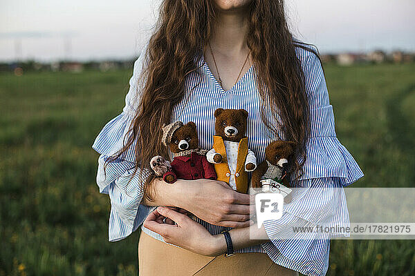 Woman holding handmade teddy bears standing in field