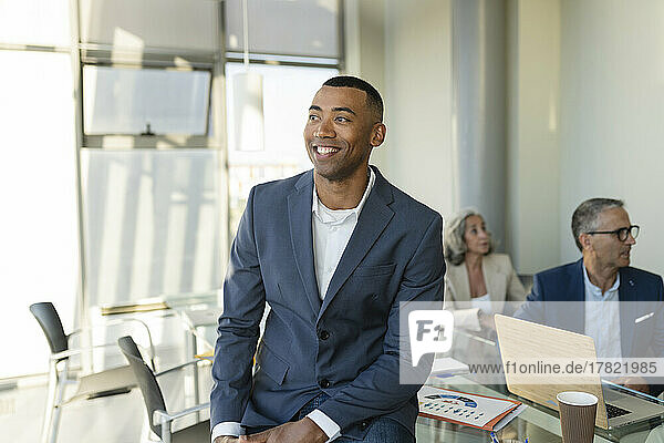 Smiling businessman sitting on table at office