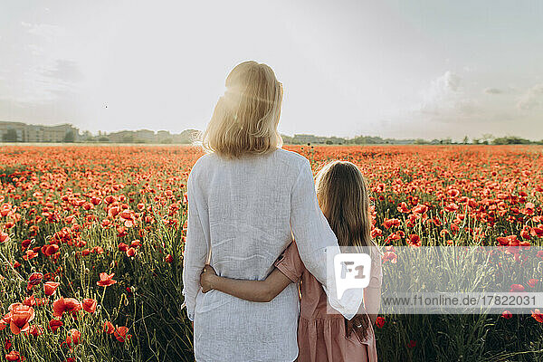 Woman and daughter standing in poppy field
