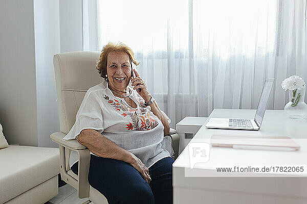 Glückliche ältere Frau  die zu Hause mit dem Handy telefoniert