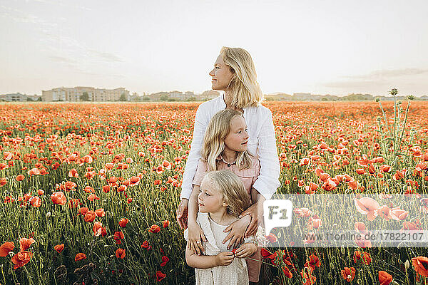 Mother with daughters standing in poppy field