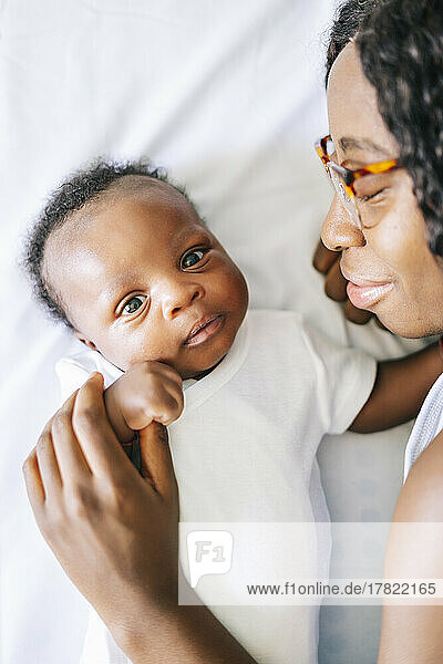 Smiling mother wearing eyeglasses lying with son at home