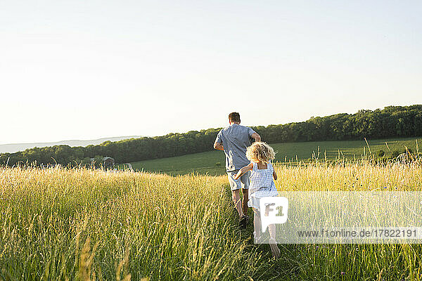 Father and daughter running together in field