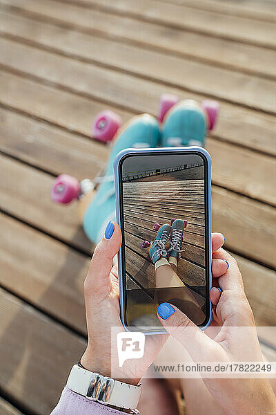 Hands of woman photographing roller skates through smart phone