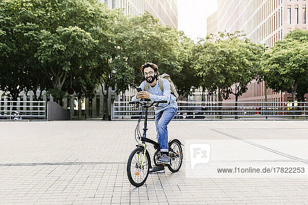 Smiling man using phone sitting on bicycle