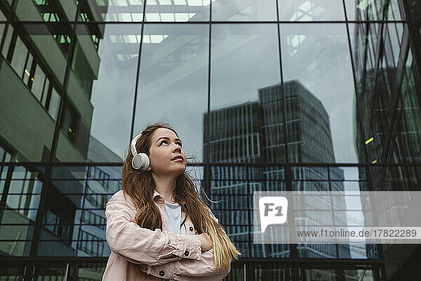 Young woman with arms crossed standing in front of glass building