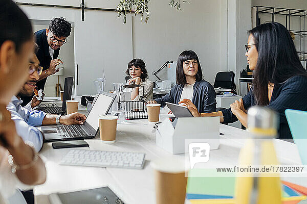 Multiracial business colleagues discussing together at desk in office meeting