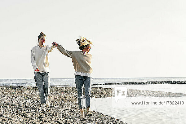 Mother and daughter holding hands walking together at beach