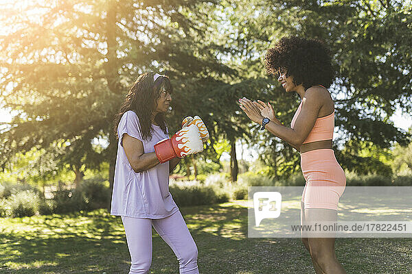 Daughter training mother for boxing in park