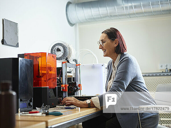 Happy technician operating SLA printer at workshop