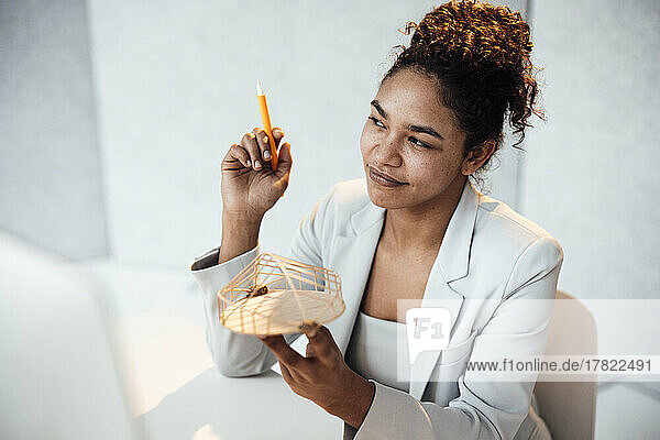 Smiling businesswoman with architectural model sitting at desk