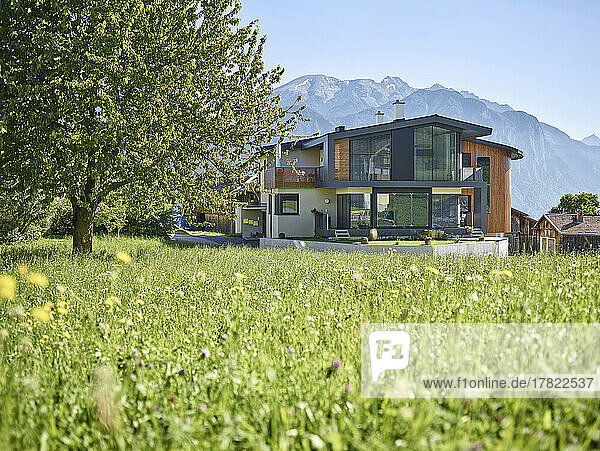 Austria  Tyrol  Springtime meadow in front of modern villa in mountains