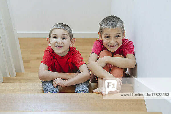 Lächelnde Brüder sitzen zu Hause auf der Treppe