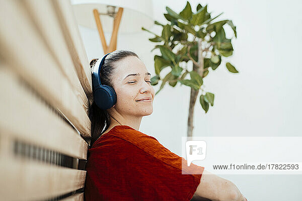 Lächelnde Frau ruht sich zu Hause mit Kopfhörern aus