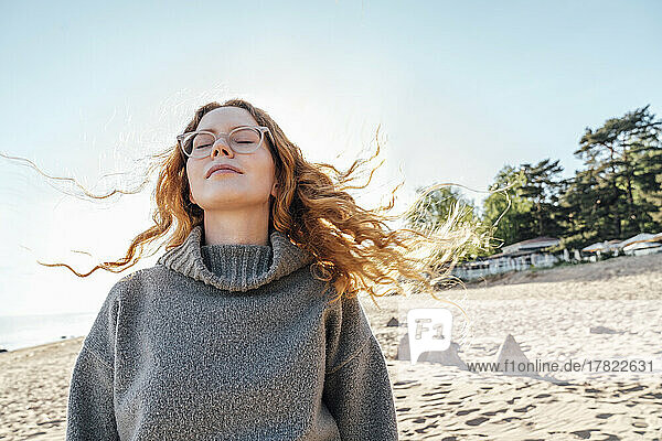 Young woman with eyes closed enjoying fresh air at beach