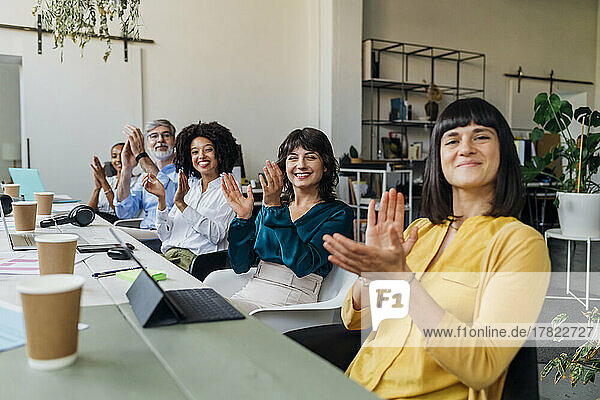 Smiling multiracial colleagues clapping hands in meeting at office