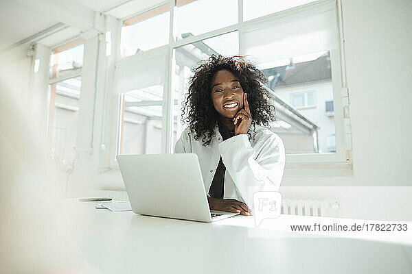 Smiling female doctor sitting with laptop at desk