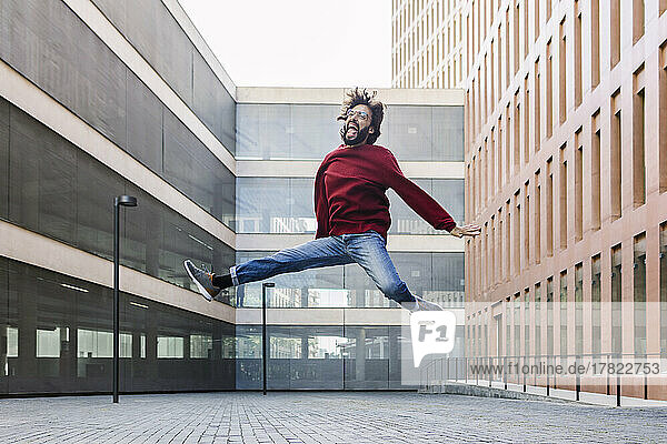 Cheerful man jumping in front of building