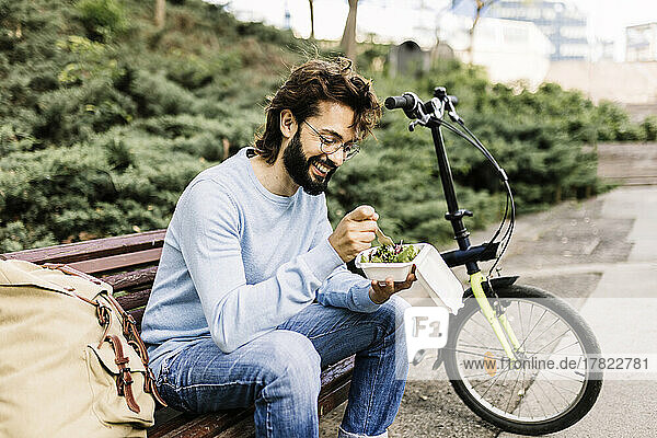 Happy man with food sitting on bench