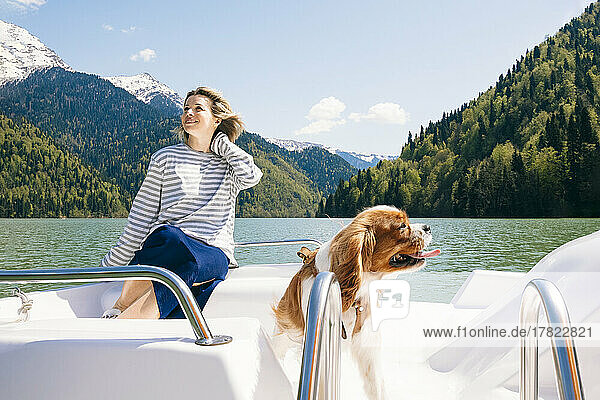 Happy woman with dog on boat at Lake Ritsa