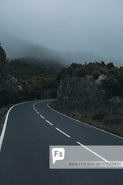 Empty long asphalt road in foggy weather