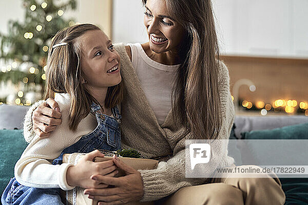 Happy mother embracing daughter sitting in living room