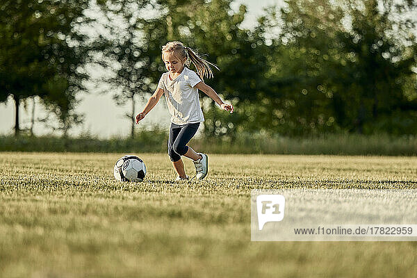 Girl playing soccer at sports field on sunny day