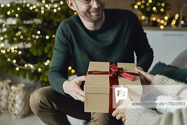 Smiling man giving gift to woman at home