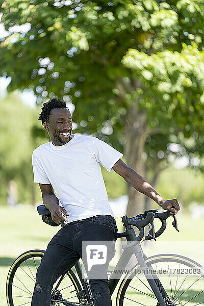 Smiling man sitting on bicycle at park