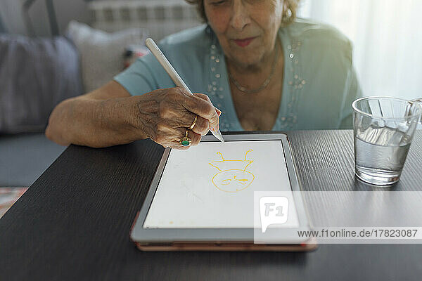 Lächelnde ältere Frau  die zu Hause einen Tablet-PC benutzt