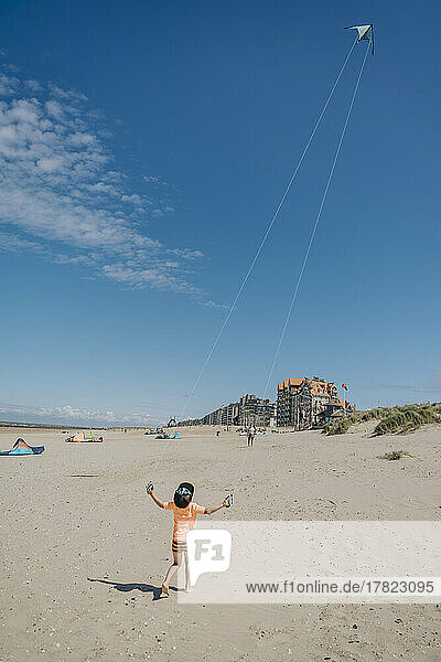 Boy flying kite on sunny day at beach