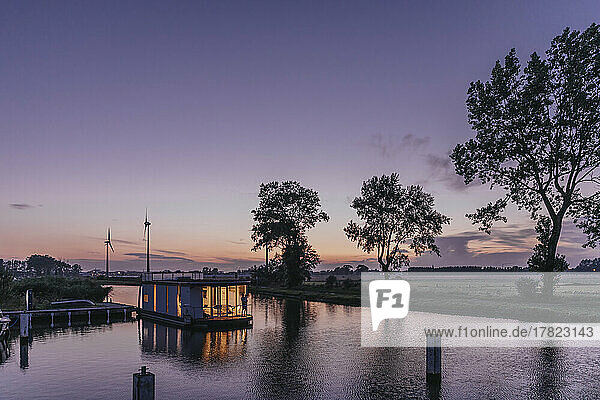 Illuminated houseboat on Yser River at sunset