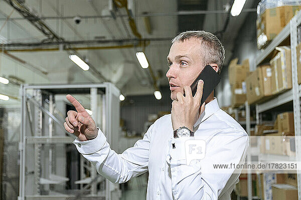 Businessman talking on mobile phone in factory